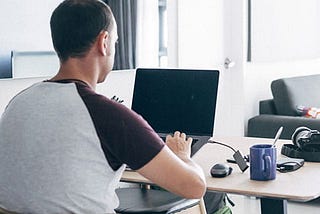 young individual typing on a laptop on a table in a living room