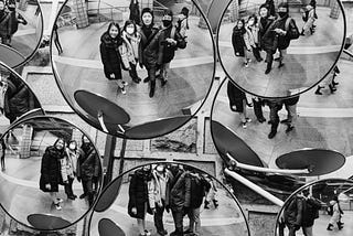 Multiple round convex mirrors showing the same Asian people in a public place.