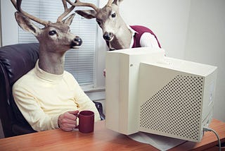 Two deer people learning how to code on an old computer