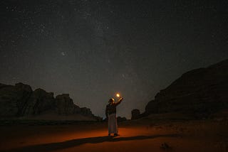 Lady holding a flaming torch in the desert at night