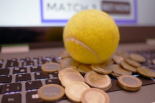 coins and a tennis ball on a computer, implying online sports betting