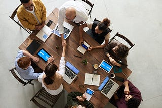 A group of people working with notebooks at a wooden table.