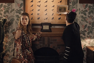 A man and woman stand next to a large chart of birds and numbers. The man is holding up a sheet next to it