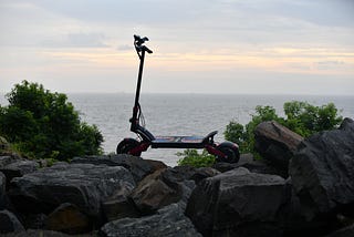 A scooter propped up on rocks overlooking the ocean.