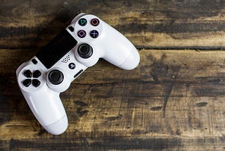 White gaming controller for Playstation on a wooden table