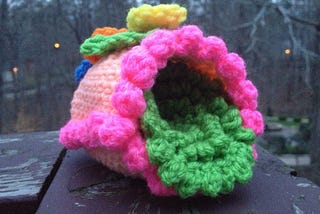 A crochet sugar egg with crochet flowers, trim, and grass