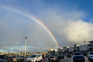 Rainbow ending in a shopping area parking lot