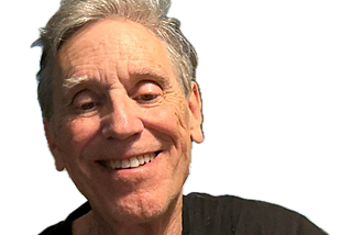 Smiling older man with gray hair wearing a black shirt, shown against a transparent background.