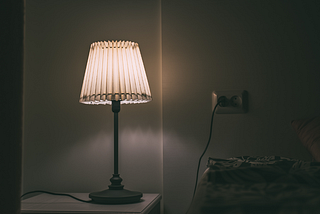 short story — image of bedside lamp in darkened room