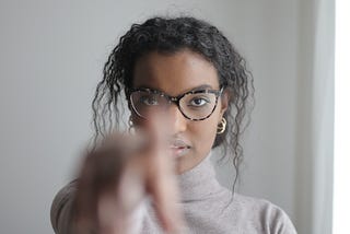 Woman teacher with glasses pointing at camera with curiosity and education