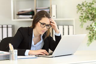 A executive staring at laptop with a stress look on her face.