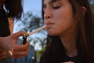Woman lighting a teenager girl’s cigarette