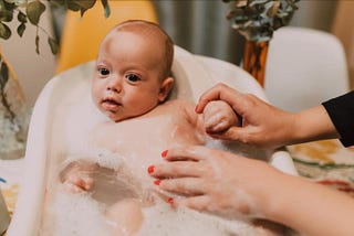 Baby being washed in baby bathtub