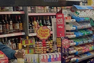 image of the interior of a london corner shop, shelves full of alcohol, sweets and vapes