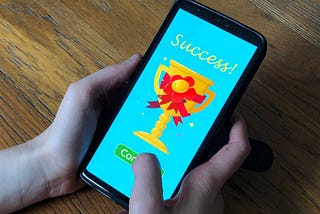 A mobile phone user with success message for an app, demonstrating a key aspect of gamification