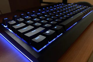 A Razer Blackwidow V4 75 keyboard on a desk, with the lighting set to a blue hue.