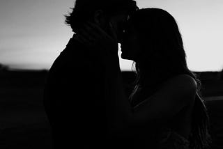Silhouette of a couple sharing a kiss at sunset, symbolizing emotional connection, presence, and intimacy.