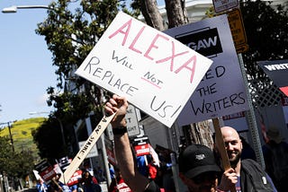 WGA striker holding up sign saying “Alexa will not replace us!”