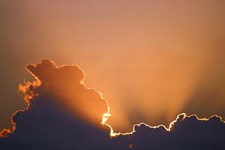 The image shows a beautiful sunset with the sun’s rays peeking through dark clouds, casting a warm, golden glow across the sky. This type of imagery symbolizes hope and serenity emerging from darkness and turmoil. It visually represents the idea of maintaining inner peace and finding light even in challenging times.