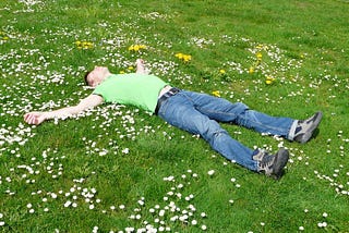 Man lying down relaxing on green grass.