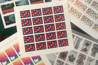 Photograph of five sheets of 20 stamps each with the themes of celebrate, Woodstock 50th anniversary, American gardens, Ruth Asawa Artist 1926–2013, and Love in the center.