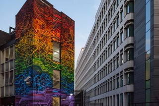 Rainbow colored “Pride Matters” mural on the side of a building in a city