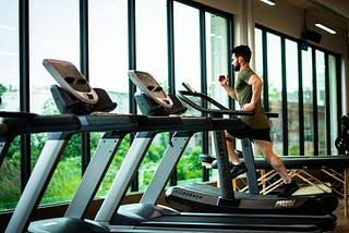 Man running on a treadmill in a gym.