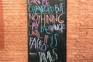 James Baldwin quote, written in chalk on a boarded up window.