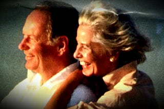 A beautiful couple smiling as they look into the sunrise.