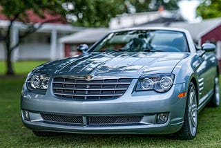 Panoramic photograph of a (likely) 2013 Chrysler Crossfire with a red polebarn in the background.