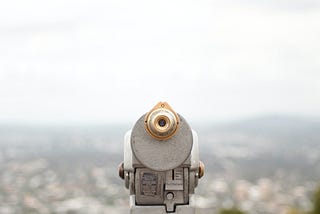 A photograph of a telescope overlooking a landscape view.