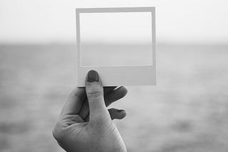 empty photo frame held over a vast ocean landscape