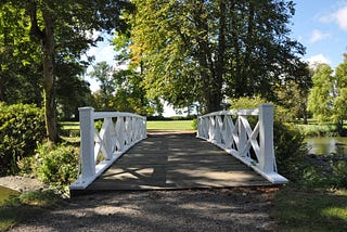 Bridge with white railings in a green park on a sunny day.