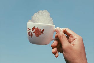 A hand holding a cup full of clouds