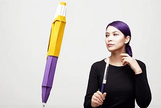 An author next to a giant pen thinking about minimalist writing