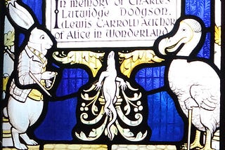 A stained glass window of the White Rabbit and the Dodo, commemorating Lewis Carroll, author of Alice in Wonderland. The White Rabbit is, as ever, anxiously checking his pocket watch.