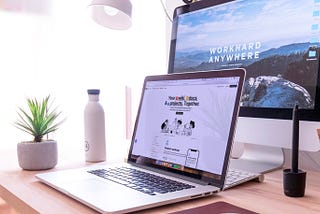 Photography of a desk with a laptop in front of a display showing Notion’s website.