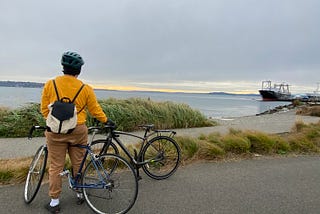 Person standing with bikes overlooking the Elliott Bay on the Elliott Bay Trail