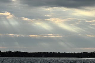 photo of sunrays through clouds over water