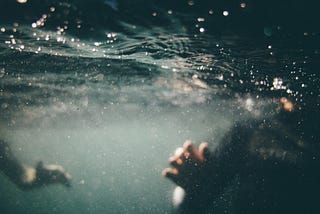Two people are partially visible, submerged in dark, turbulent water