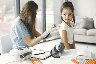 A health professional conducts a checkup for a young girl.