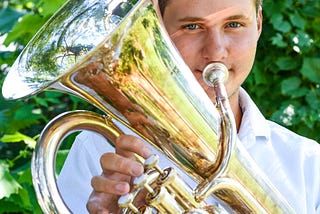 Declan holding his euphonium, light reflected on his face