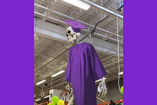 An oversize skeleton wearing a purple hat and gown.