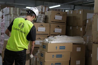 Worker in a warehouse wearing a wearable device on the back of his shirt