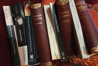 A photograph of a selection of several of the Victorian novels mentioned in this story, lined up together and propped against a sofa cushion. Photograph by Taryn Parker-Holmes, the author.