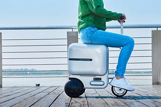 Person riding on a three-wheel electric suitcase.