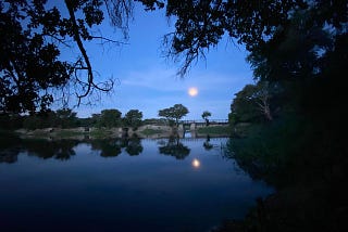 A full moon setting over still water near the Okavango Delta