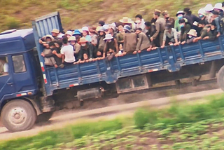 Dozens of North Koreans packed tightly on the back of a large blue truck