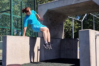 Woman doing a corner vault over a hip-high concrete wall