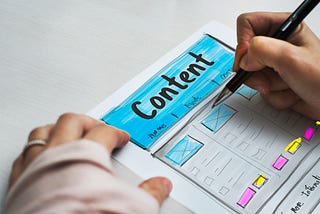 Mão feminina desenhando um wireframe com a palavra “Content” em destaque